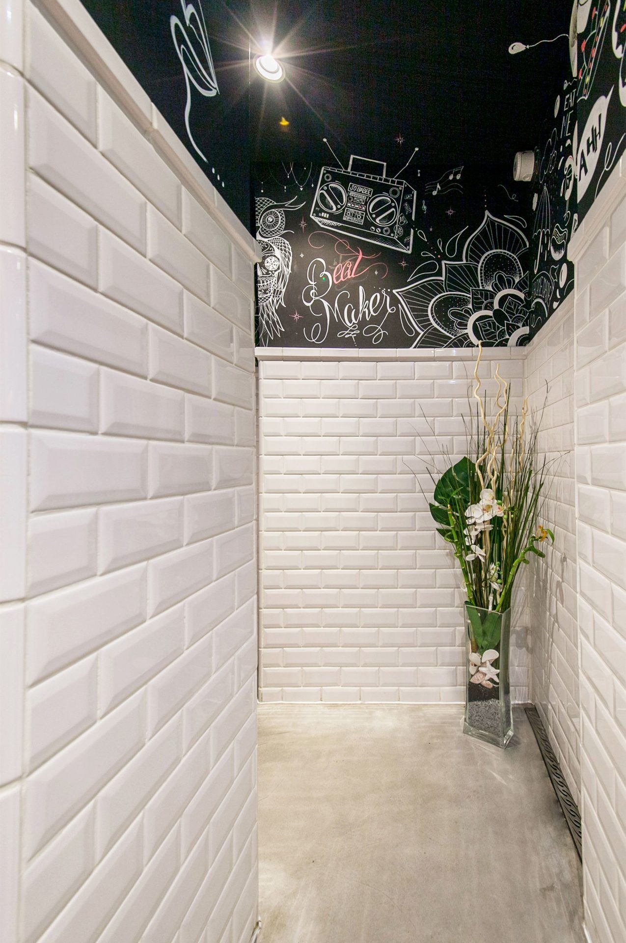 Couloir sanitaire complètement carrelé avec illustration d'un artiste