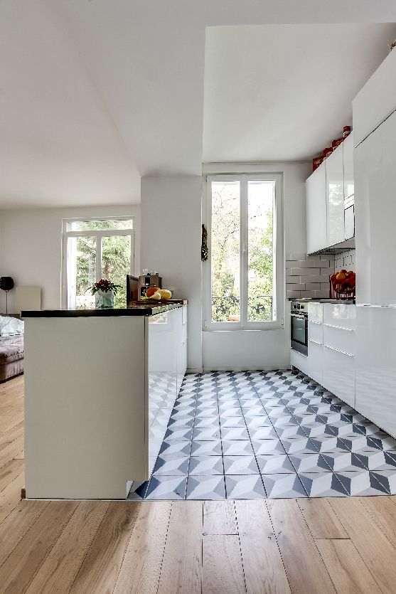 Vue sur la cuisine ouverte séparée au sol par un carrelage à modèle géométrique